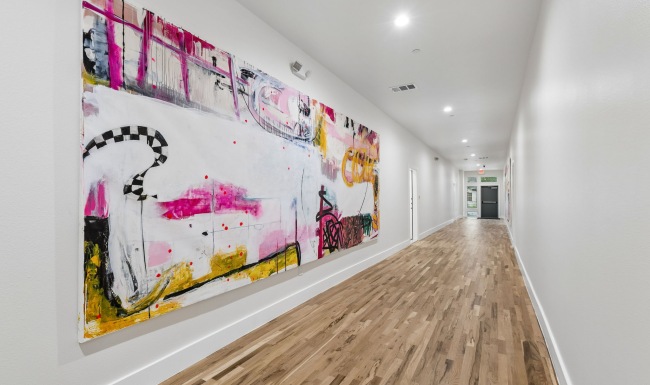 a long hallway with wood floors and art on the wall