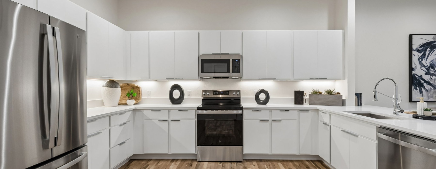 large kitchen with white cabinets wood floors and stainless steel appliances
